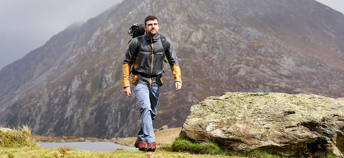 Man in windproof and backpack hiking past Snowdon